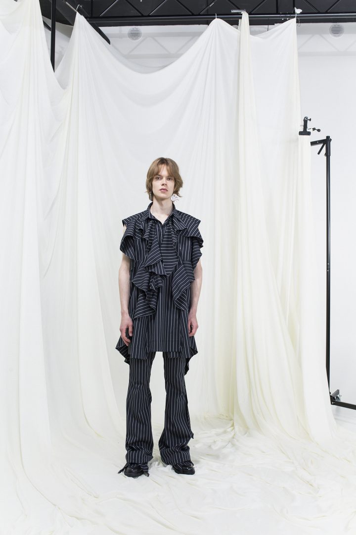 Model wearing a ruffled dark-blue and white pinstripe top and pinstripe bell-bottomed trousers