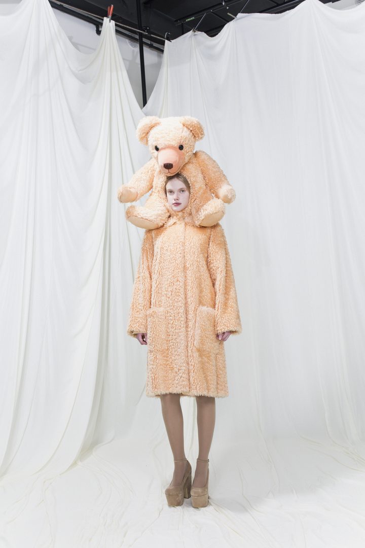 Model wearing a brushed fur coat with a teddy bear as a hood.