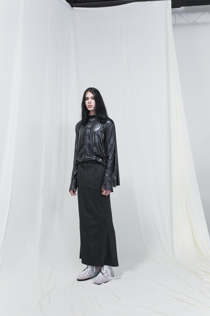 Model wearing a shiny draped shirt with a skirt resembling a pair of trousers